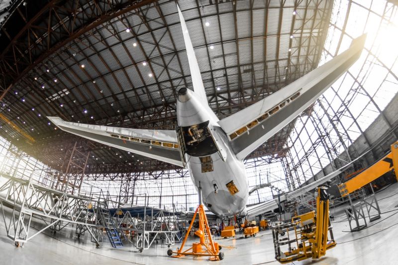 In einem Hangar steht ein großes Passagierflugzeug, aufgenommen von schräg unten hinten.