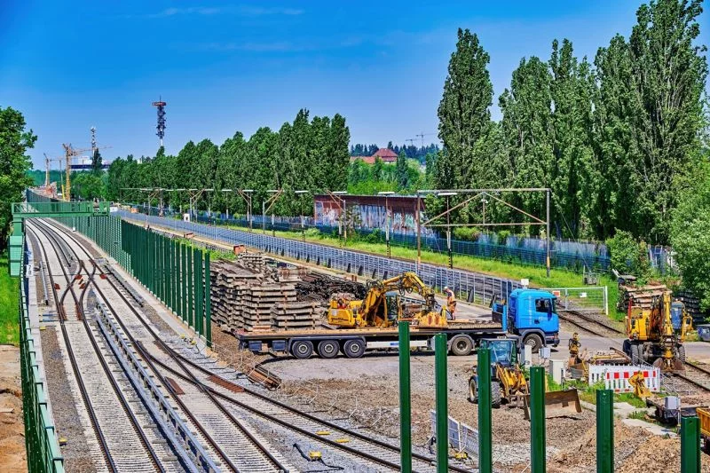 Eisenbahnbaustelle mit Baufahrzeugen und gestapeltem Material.