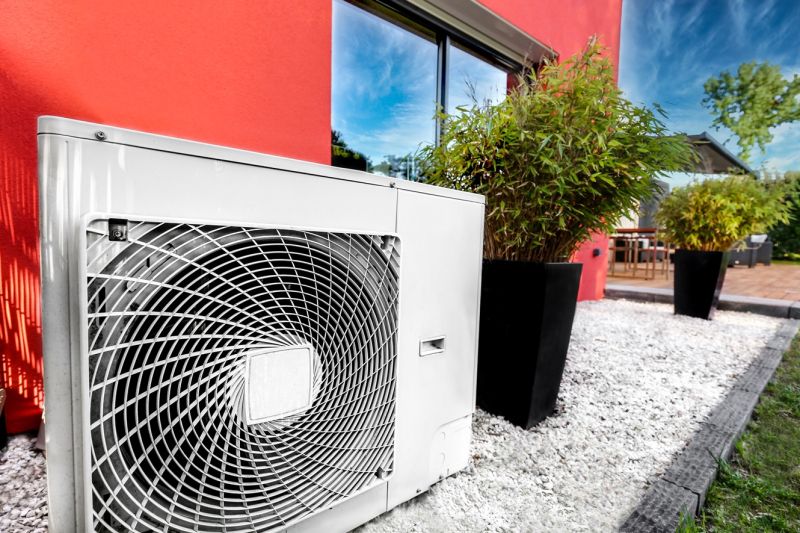 Eine Luftwärmepumpe steht vor einem modernen Einfamilienhaus in einem Schottergärtchen.