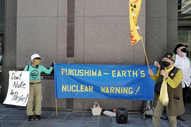 Einige Menschen mit Mundschutz stehen vor dem Eingang zum japanischen Konsulat in San Francisco und halten Transparente für einen atomfreien Pazifik und über die globale Warnung von Fukushima.