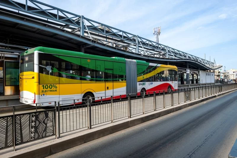 Grün-Gelb-weiß-roter Gelenkbus mit der Aufschrift: 100 Prozent elektrisch.