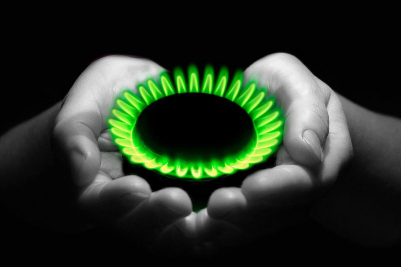 Fotomontage: Eine grüne Gasflamme wird wie ein Geschenk in zwei geöffneten Handflächen dargeboten.