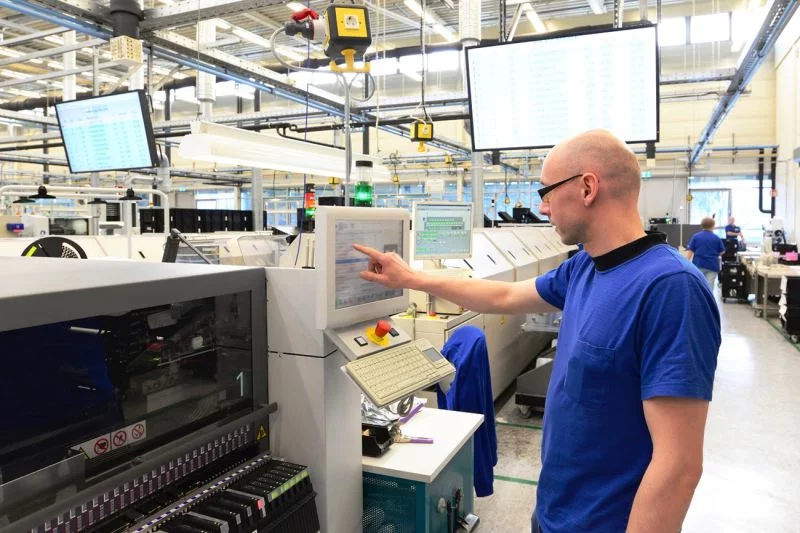 Ein Mitarbeiter bedient eine Maschine in einer Hightech-Werkhalle.