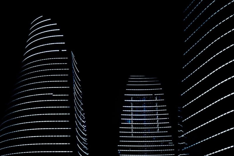 Die drei Flame Towers in Baku in sparsamer nächtlicher Beleuchtung durch waagerechte weiße Lichtstreifen in jeder Etage.