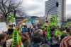 Eine Menschenmenge mit vielen grünen und bunten Fahnen und selbstgebastelten Schildern.